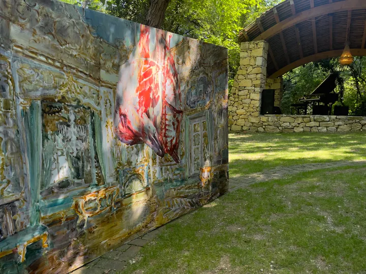 Large painting with red figure displayed outdoors
